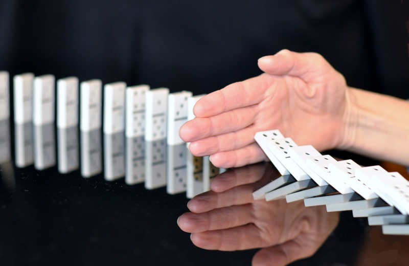 bàn tay chặn quân cờ domino sụp đổ
